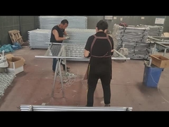 Los trabajadores están usando alambre para conectar la cerca de enlace de cadena y el tubo del marco